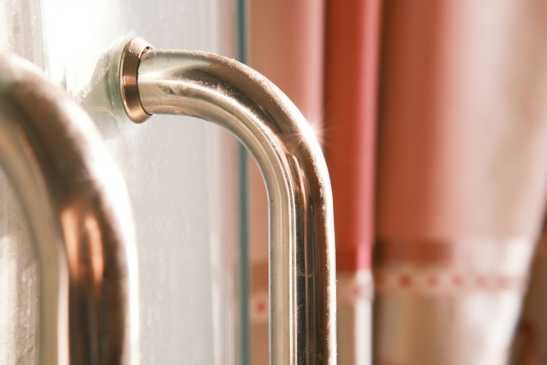 Stainless steel door handle for an aluminium bathroom door